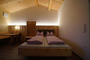 a bedroom with a bed in a room with a desk at NEUE Ferienwohnungen auf dem Gebreitnerhof, Urlaub auf dem Bauernhof in Bressanone