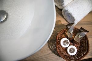 Una cesta de artículos de tocador sobre una mesa junto a un lavabo. en Angelica's Deluxe Rooms in Adamas, en Adamas