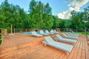a row of white lounge chairs on a wooden deck at APARTAMENTY SPA & RESORT BUKOWIEC in Polańczyk