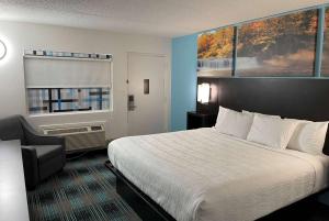 une chambre d'hôtel avec un lit et une chaise dans l'établissement Days Inn by Wyndham Calhoun GA I-75 and US-41, à Calhoun