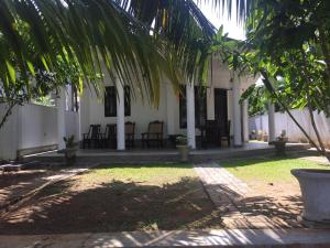 a building with chairs and a palm tree in front of it at Avendra Holiday Inn Weligama in Weligama