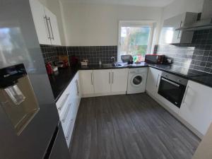 a kitchen with white cabinets and a washer and dryer at Paisley Central Apartment #4 in Paisley