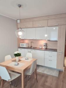 a kitchen with a wooden table and white cabinets at Apartament Baltic in Świnoujście