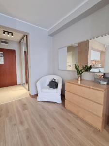 a living room with a white chair and a dresser at Apartament Baltic in Świnoujście