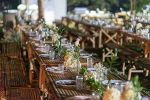 una fila de mesas de madera con platos y flores. en Banviewnam Camping & Resort, en Bān Tha Pu Deang
