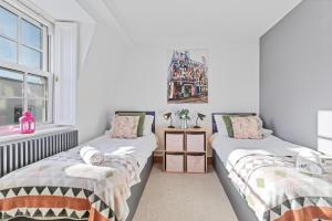 two twin beds in a room with a window at Pebble Mews House - By My Getaways - parking for one small car in Brighton & Hove
