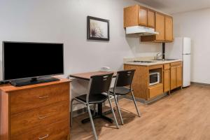 a small kitchen with a desk with a tv and chairs at WoodSpring Suites Abilene in Abilene