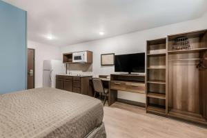 Habitación de hotel con cama y escritorio con TV. en WoodSpring Suites Charlotte - University Research Park, en Charlotte