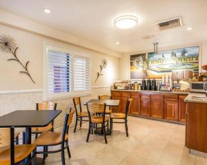 a dining room with tables and chairs and a kitchen at Rodeway Inn & Suites Colton-Riverside in Colton