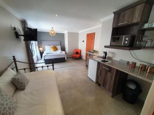 a bedroom with a bed and a kitchen with a couch at Sleep@84 in Dullstroom