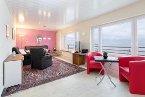ein Wohnzimmer mit einem roten Sofa, einem Tisch und Stühlen in der Unterkunft Haus Seestern Grömitz Haus Seestern an der Kurpromenade, Wohnung 1 in Grömitz