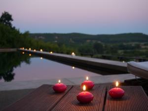 four red candles sitting on a table next to a pool at La Maison des Sarrasins in Beynac-et-Cazenac