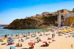 a group of people on a beach with umbrellas at Casa Albufeira in Albufeira