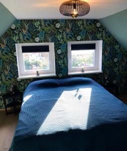 a bedroom with a blue bed and two windows at Paradiesje 3 in Leer