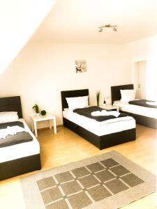 Cette chambre comprend 3 lits et un tapis. dans l'établissement SUNNYHOME Monteurwohnungen und Apartments nahe Regensburg, à Nittendorf