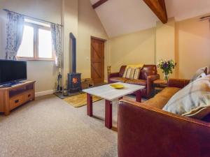 a living room with a couch and a table and a tv at Cider House, Oosland Farm in Bidford