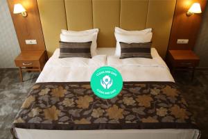 a hotel room with two beds with a green sign on it at Hotel Golden Tulip Varna in Varna City