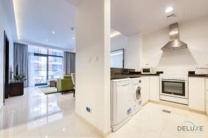 Una cocina blanca con lavadora y secadora. en Sleek 1BR Apartment at Celestia Dubai South by Deluxe Holiday Homes, en Dubái