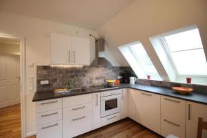 a kitchen with white cabinets and a sink at Haus Longholmen in Ording