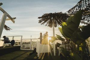 a bride and groom standing on a balcony with the ocean at Sunset Destination Hostel in Lisbon