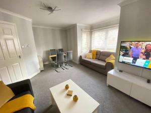ein Wohnzimmer mit einem Sofa und einem Flachbild-TV in der Unterkunft Paisley Central Apartment #2 in Paisley