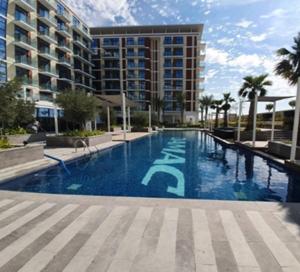 una gran piscina frente a un edificio en Sleek 1BR Apartment at Celestia Dubai South by Deluxe Holiday Homes, en Dubái
