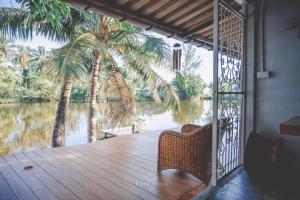 a porch with a view of a river and palm trees at Thipwararom homestay in Takua Pa