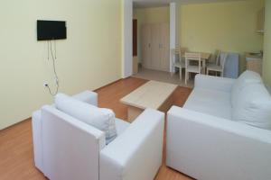 una sala de estar con 2 sofás blancos y una mesa. en Aparthotel Anixi, en Obzor