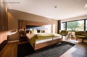a bedroom with a large bed and a large window at Sporthotel Grafenwald in Daun