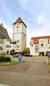 un bâtiment avec une tour d'horloge dans un parking dans l'établissement Residence du Vieux Chateau jardin & parking gratuit, à Mulhouse