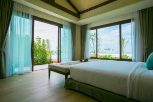 a bedroom with a large bed and large windows at Triple Tree Beach Resort in Cha Am
