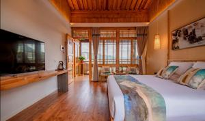 ein Schlafzimmer mit einem großen Bett und einem TV in der Unterkunft Floral Tengchong Mountain Residence in Tengchong
