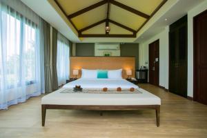 a bedroom with a large bed with a large window at Triple Tree Beach Resort in Cha Am