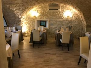 comedor con mesas y sillas y pared de piedra en Auberge Gardoise, en Vallérargues