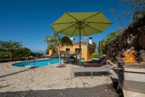 a large green umbrella sitting next to a swimming pool at CASA VAN DE WALLE in Tijarafe