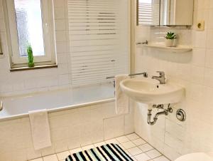 a white bathroom with a sink and a bath tub at SUNNYHOME Monteurwohnungen und Apartments nahe Regensburg in Nittendorf