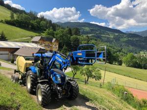 Niebieski traktor zaparkowany na zboczu wzgórza w obiekcie Appart Sölkhof w mieście Schöder