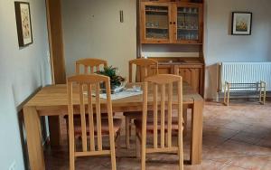 mesa de madera con 4 sillas y cocina en Ferienhaus Geltinger Birk, en Gelting