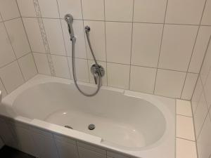 e bagno piastrellato bianco con vasca e doccia. di Apartment Schmuck a Bad Abbach