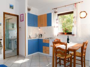 a kitchen with blue cabinets and a table with chairs at Apartment Radmila - MLK141 by Interhome in Gostinjac