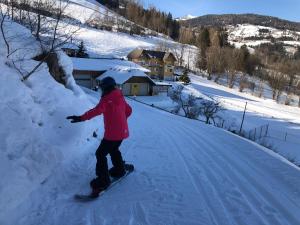 eine Person, die auf einer schneebedeckten Straße mit einem Snowboard fährt in der Unterkunft Appart Sölkhof in Schöder