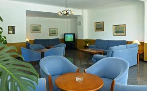 a waiting room with blue chairs and a tv at Hotel Condemar in Portopetro