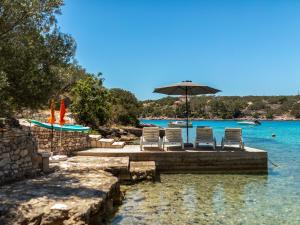 a group of chairs and an umbrella on a dock in the water at Holiday Home Nataly by Interhome in Vela Luka