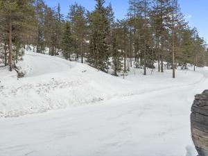 a snow covered road in a forest with trees at Holiday Home Rukakämmekkä by Interhome in Ruka