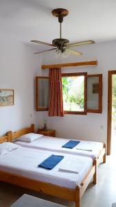 two beds in a room with a ceiling fan at Villa Alexandra in Roda