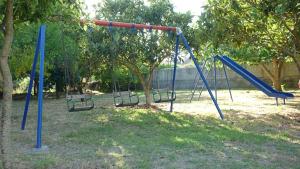 a playground with blue swings in a park at Villa Alexandra in Roda