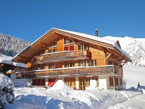 ein großes Holzgebäude mit Schnee auf dem Boden in der Unterkunft Am Gilsbach in Adelboden