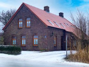 ノルデンにあるApartment Krause by Interhomeの雪の赤い屋根のレンガ造りの家