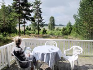 a woman sitting at a table on a deck with a laptop at Chalet Forsviken - VMD049 by Interhome in Karlstad