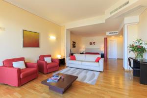 斯特雷薩的住宿－Hotel Residence La Luna Nel Porto，客厅配有白色沙发和2把红色椅子